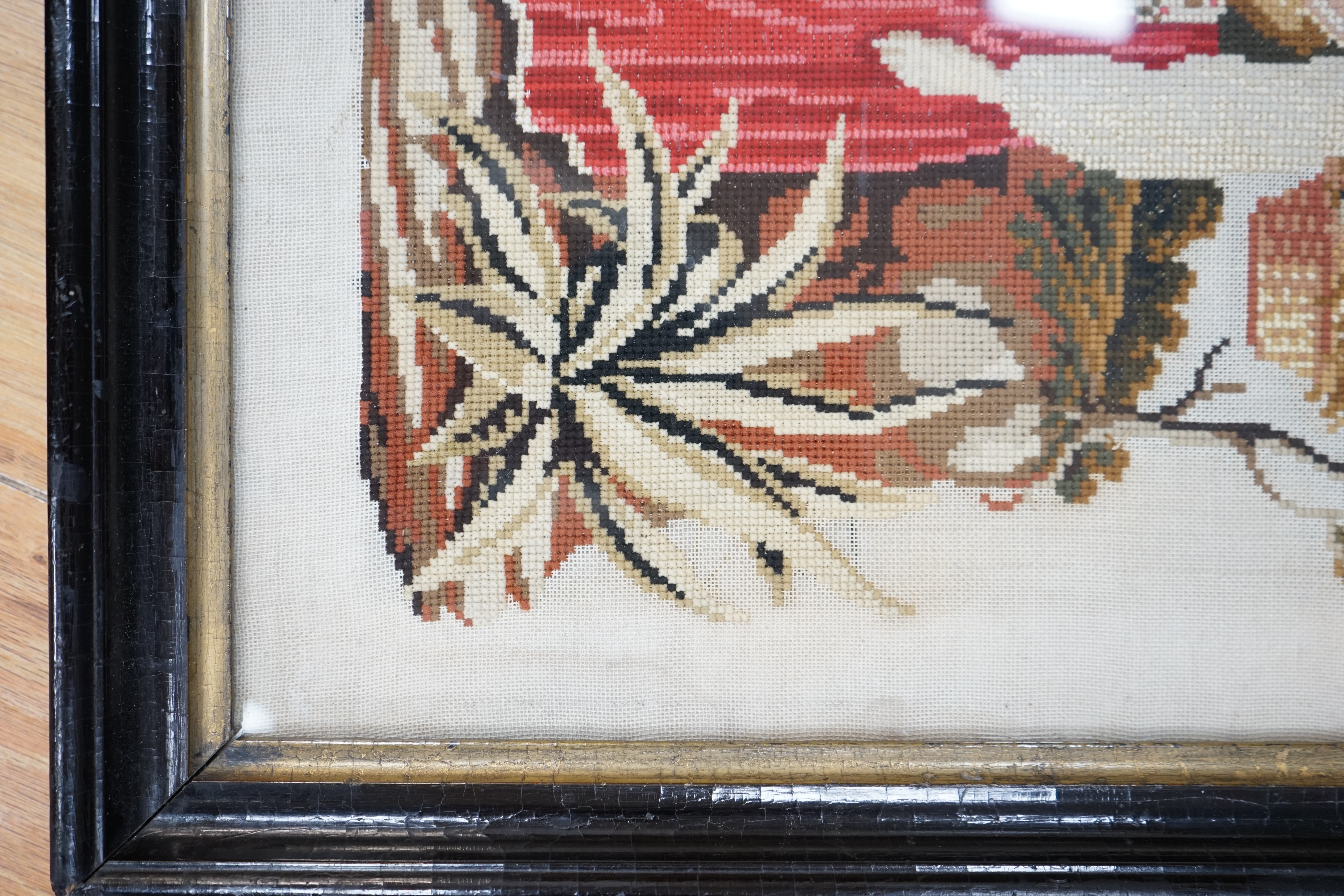 A framed 19th century Berlin wool worked embroidery of a peasant girl carrying panniers by a church, with the steeple in the background, 30cm x 38cm